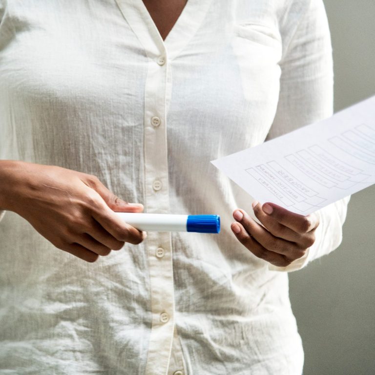 Eine Person hält ein Blatt Papier und einen Stift in den Händen.